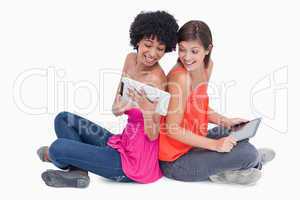 Laughing teenagers looking at a tablet PC while sitting cross-le
