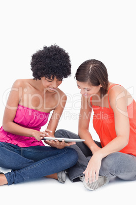 Teenagers attentively looking at a tablet computer against a whi