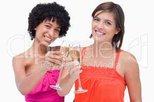 Young women celebrating an event by clinking glasses of champagn