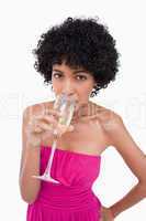 Young woman drinking a glass of champagne against a white backgr