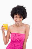 Young smiling woman holding a glass of orange juice