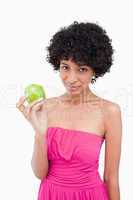Attractive young woman showing a green apple while looking at th
