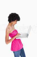 Attractive teenager standing upright while holding a laptop