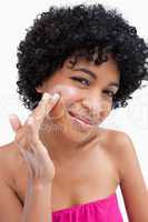 Smiling woman putting some cream on her face