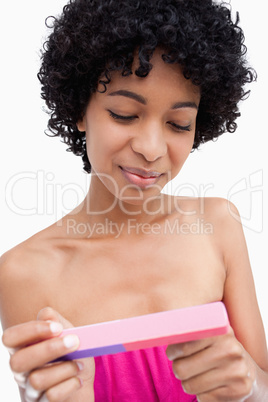 Young woman filing her nails with her pink nail file