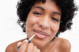 Beautiful young woman using lip brush while making-up