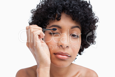 Young woman applying make-up while putting on eye-shadow