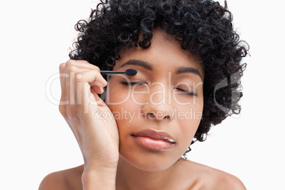Young woman closing her eyes while applying eye-shadow