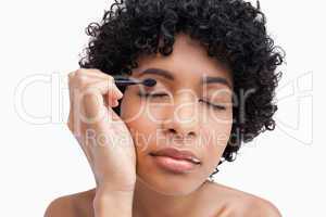 Young woman closing her eyes while applying eye-shadow