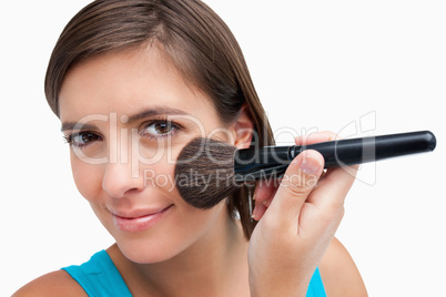 Smiling teenager using a powder brush with a mischievous look