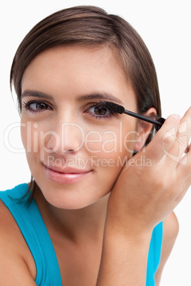 Young woman applying mascara on her lashes