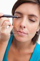 Young woman using an eye pencil to apply make-up