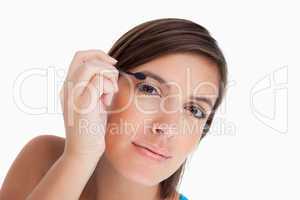 Beautiful teenager leaning her head while applying eyeshadow