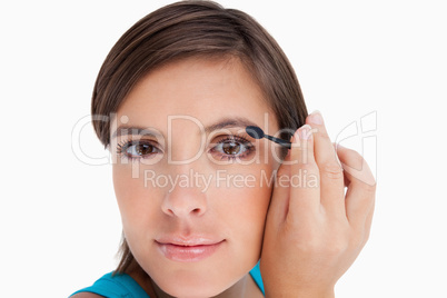 Young woman looking at the camera putting eyeshadow on her eyeli