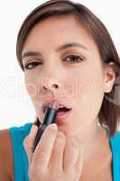 Attractive teenager applying lipstick against a white background