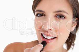 Smiling teenage girl applying make-up while putting on lipstick