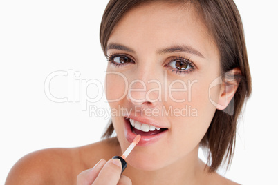 Beautiful teenager using a lip brush to apply lip gloss