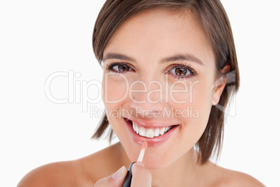 Teenager smiling while applying lip gloss with a lip brush