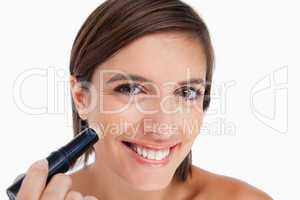 Smiling young woman applying natural foundation on her face