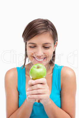 Smiling teenager looking at a green apple placed on her hands cr