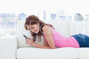 Young woman attentively looking at her cellphone while sending a