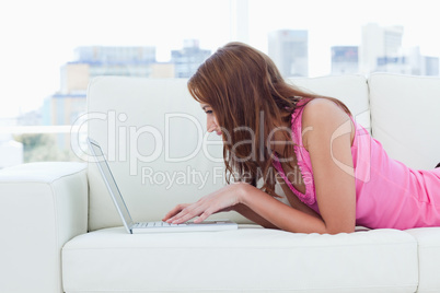 Young woman looking at her laptop while using the keyboard