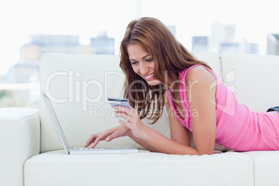 Young woman looking at her credit card to make purchases on inte