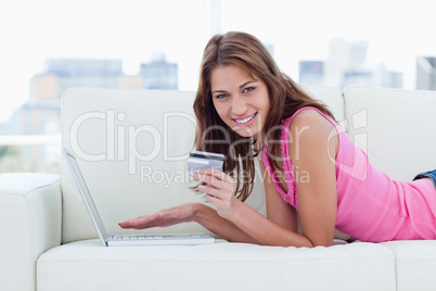 Young woman holding a credit card while showing a great smile