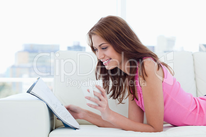 Young woman reading a magazine on a sofa with a cup of coffee