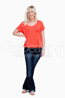 Smiling teenager standing upright with a hand on hip and legs cr