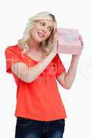 Smiling young woman looking at a gift while holding it