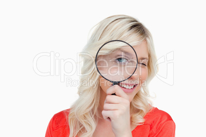 Woman looking through a magnifying glass while blinking an eye