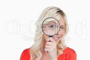 Woman looking through a magnifying glass while blinking an eye