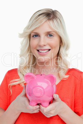 Smiling teenage girl holding a pink piggy bank in her hands