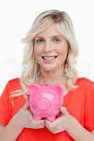 Smiling teenage girl holding a pink piggy bank in her hands