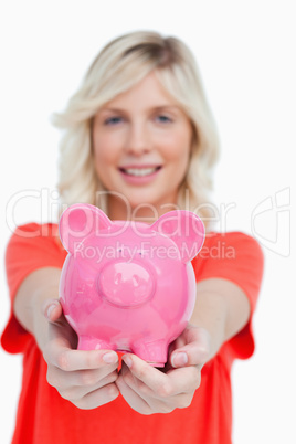 Pink piggy bank held by a smiling attractive woman