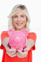 Pink piggy bank held by a smiling attractive woman