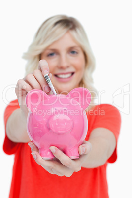 Piggy bank getting dollar notes from a young woman