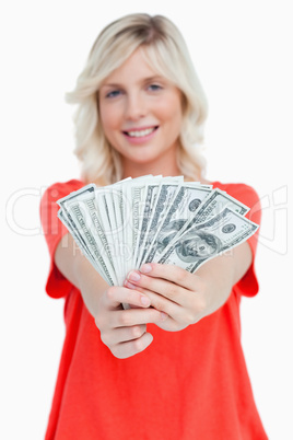 A fan of dollar notes held by a smiling attractive woman