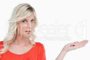 Woman looking at the camera while holding vitamins in her hand