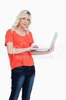 Serious blonde woman holding a laptop in her left hand