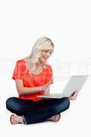 Young blonde woman waving her hand in front of her laptop