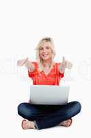 Young woman sitting cross-legged with her thumbs up