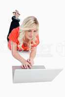 Attractive blonde woman using the touchpad of her laptop while l
