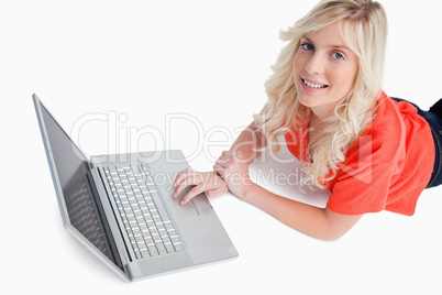 Smiling young woman using her laptop while lying down