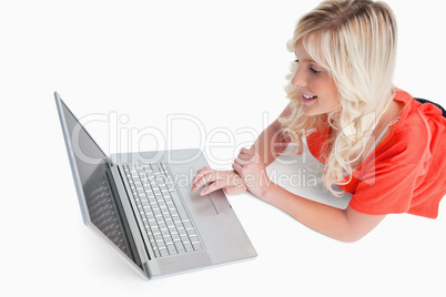 Smiling woman lying down while looking at her laptop