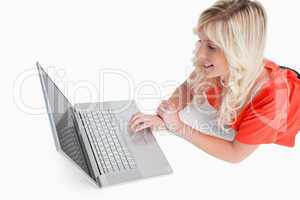 Smiling woman lying down while looking at her laptop