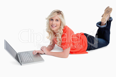 Smiling blonde woman crossing her legs in front of her laptop