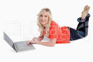 Smiling blonde woman crossing her legs in front of her laptop