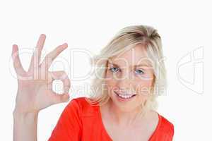 Smiling woman showing the OK sign while looking straight at the